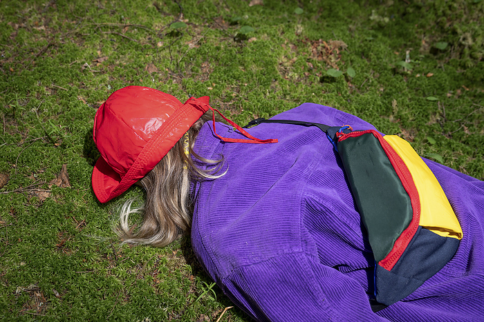 Woman wearing red bucket hat lying in forest