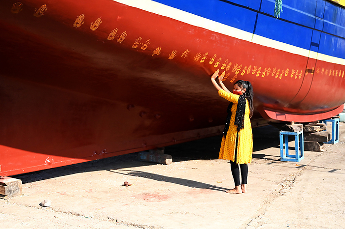 Daughter of boat owner performs puja on new boat by making hand prints along its hull prior to maiden launch, Vanakbara, Gujarat Daughter of boat owner performs puja on new boat by making hand prints along its hull prior to maiden launch, Vanakbara, Gujarat, India, Asia, Photo by Annie Owen