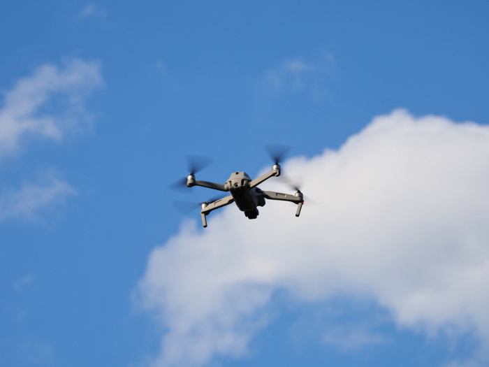 Photo looking up at drone taking aerial photos in blue sky