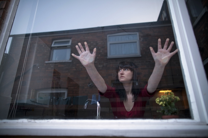 Woman in kitchen leaning on window