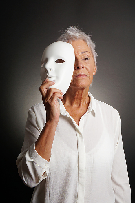 serious mature woman revealing face behind mask