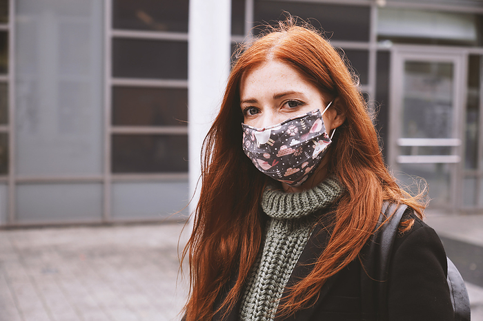 young woman wearing everyday cloth face mask outdoors in city