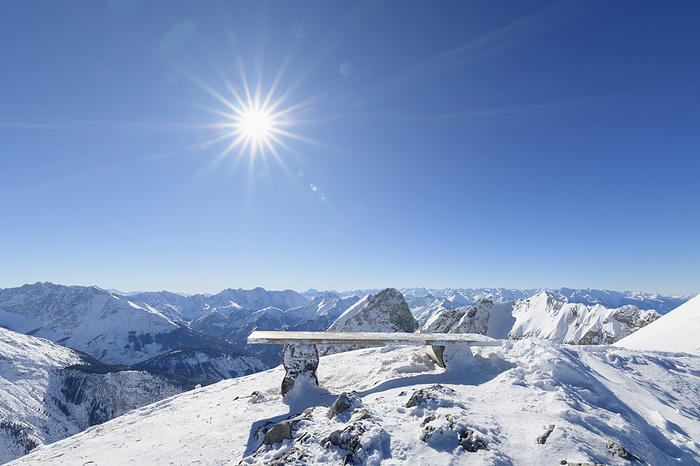 Bench on Karwendel mountainrange with sun in winter