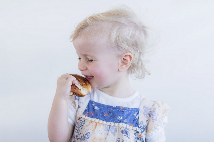 Toddler girl eating pastry indoors