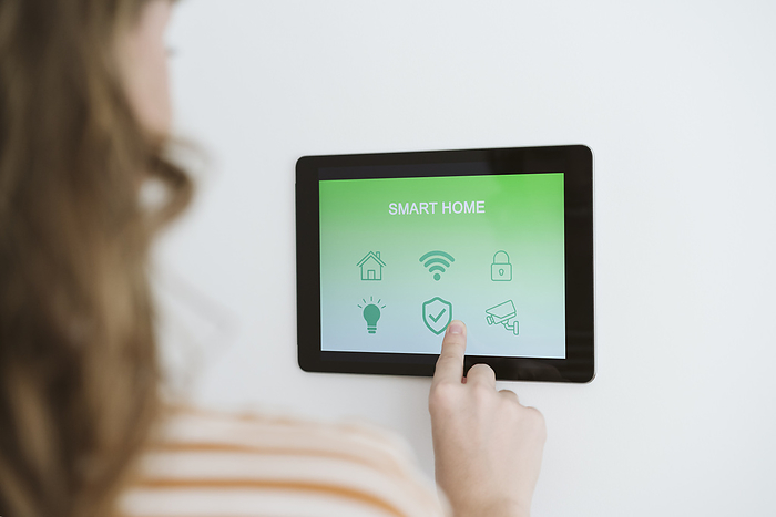 Close-up of woman using digital tablet with smart home app on the wall, Photo by Eva Blanco