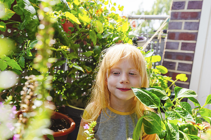 Smiling girl standing amidst plant in balcony, Photo by Irina Heß