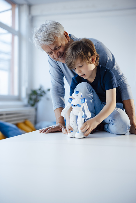 Boy with robot model by smiling grandfather at home, Photo by Joseffson