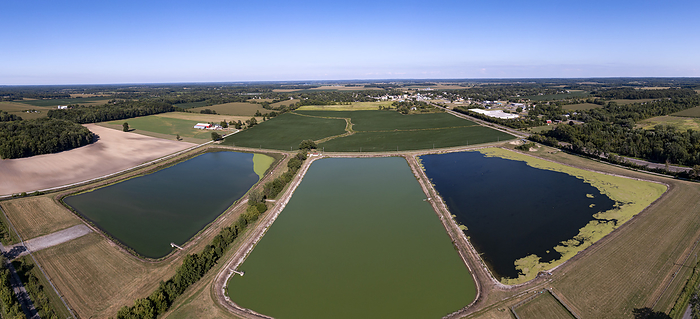 Wastewater stabilization lagoons, aerial photograph Aerial photograph of wastewater stabilization lagoons for the village of Three Oaks, Michigan, USA, seen in the distance. The lagoons treat wastewater as bacteria react with organic material, rendering it less harmful before it is discharged into the environment., by JIM WEST SCIENCE PHOTO LIBRARY