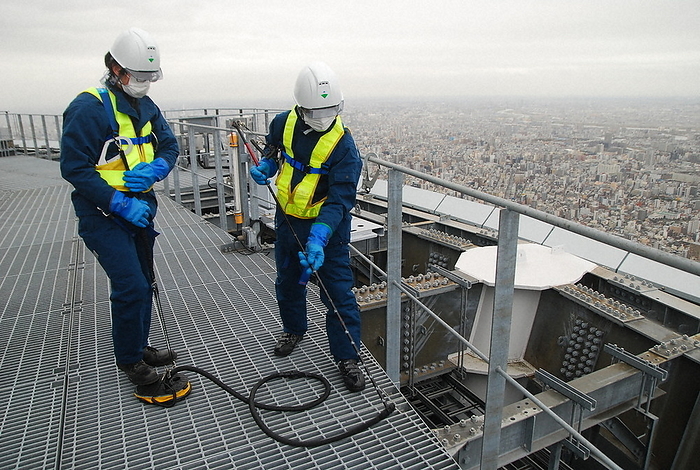 Demonstration of snow clearing at a height of 375 meters above the ground. A hose connected to a foot powered pump blows air to blow away snow that has accumulated in the crevices of the grating  metal scaffolding . Demonstration of snow removal at 375 meters above the ground. A hose connected to a foot powered pump blows air to blow away snow that has accumulated in the gaps between the grating  metal scaffolding  of the Tokyo Sky Tree.