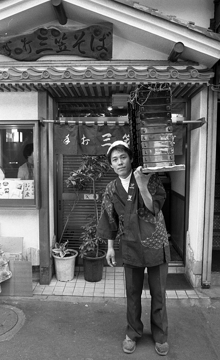 From the streets of the world Tokyo   The downtown atmosphere  1985   Japan: 1985, Tokyo   A delivery man carries on his shoulder a stack of soba  buckwheat noodles  containers in Tokyo s Taito ward.  Photo by Fujifotos AFLO   3618 