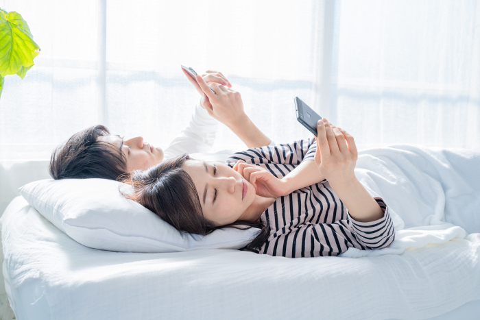 Japanese couple looking at their phones in bed.
