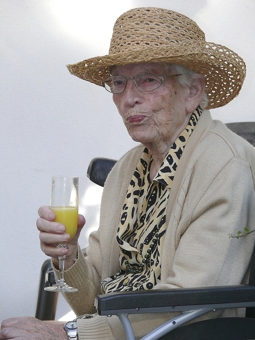 Old woman 95 years old, portrait with orange juice in champagne glass, Photo by BA-Geduldig