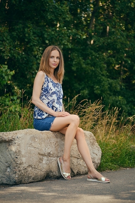 Girl in sleveless blouse and jeans skirt having rest at country recreation area, enjoying fresh air and calmness, Photo by Aleksei Isachenko