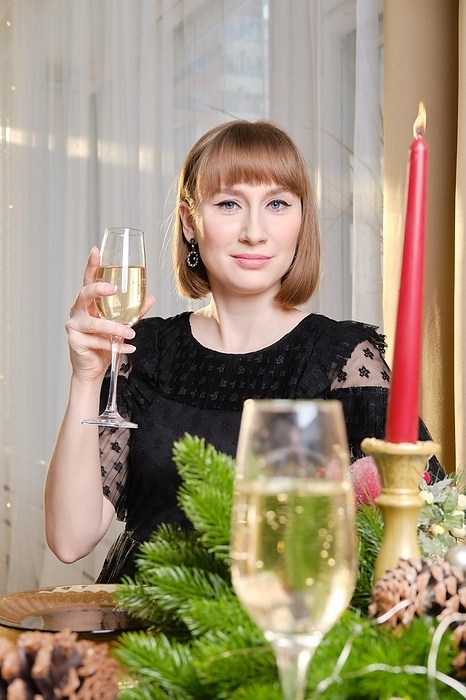Beautiful young woman with a glass of sparkling wine in hand behind the fective table, Photo by Aleksei Isachenko