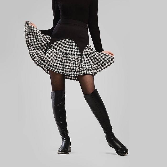 Slender female legs in tall boots and little skirt over grey background, Photo by Aleksei Isachenko