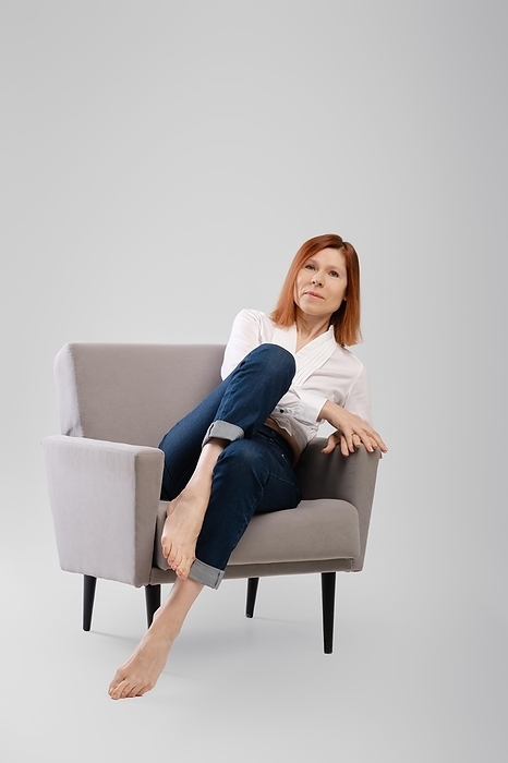 Middle age woman relax in cozy armchair. Studio concept of carefree life, Photo by Aleksei Isachenko