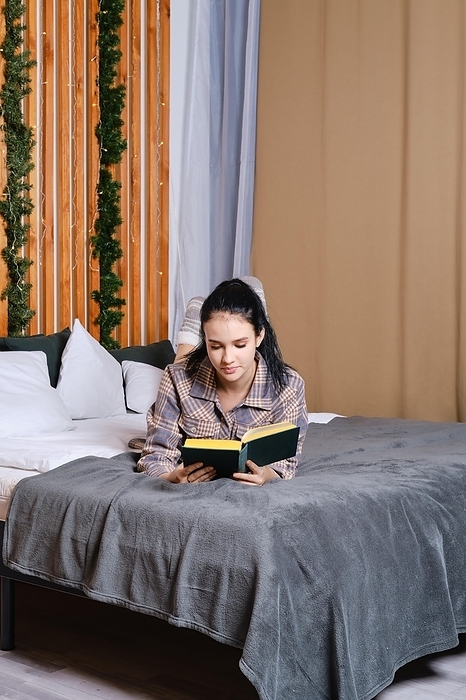 Clever young woman reading the book in bed during vacation, Photo by Aleksei Isachenko