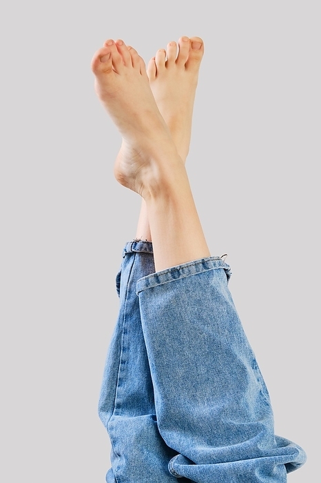 Bare female legs in boyfriend jean on grey background, Photo by Aleksei Isachenko