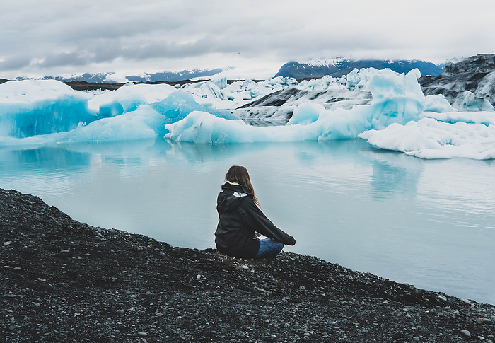 woman meditating near lake with iceberg