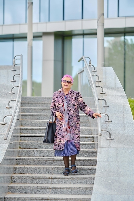 Old woman with pink hair in cashmere coat and hand bag descending the stairs, Photo by Aleksei Isachenko