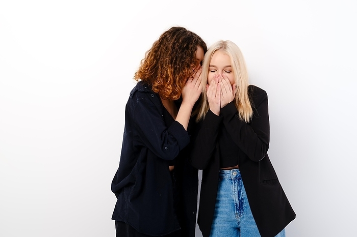 Two young teenager girls gossip and laugh over white background, Photo by Aleksei Isachenko