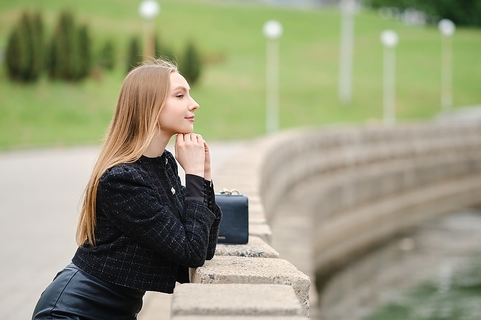 Cute woman leans against the railing and looks thoughtfully at the river, Photo by Aleksei Isachenko