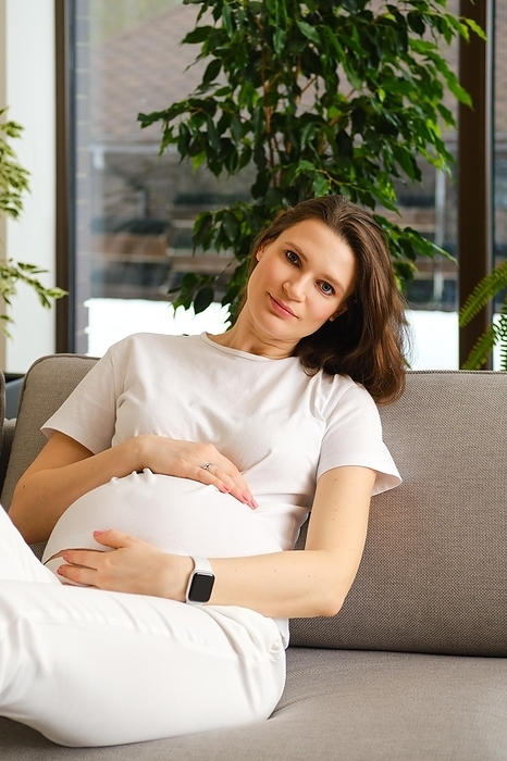 Beautiful pregnant woman having rest on sofa at home, Photo by Aleksei Isachenko