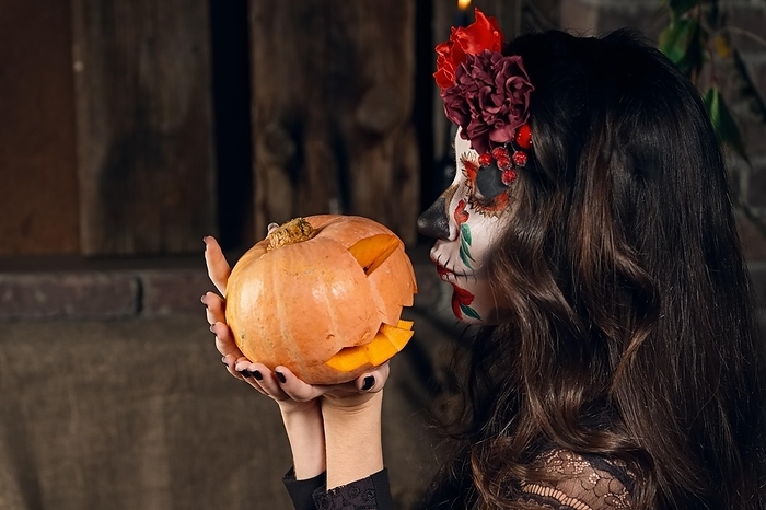 Young woman with sugar skull makeup playing with pumpkin. Face painting art, Photo by Aleksei Isachenko