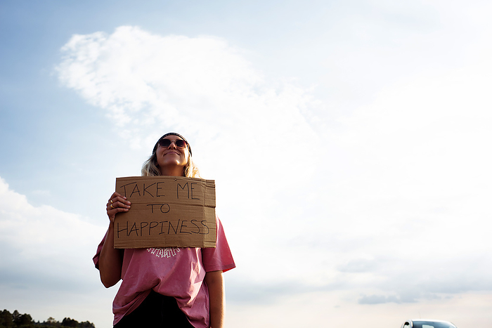 woman holding a sign protesting take me to happiness