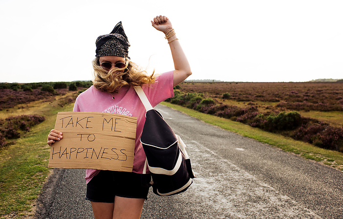 woman protesting with a sign saying take me to happiness