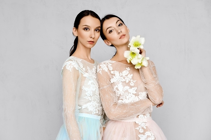 Two beautiful young women in transparent tulle dresses with lace posing in identical manner, Photo by Aleksei Isachenko