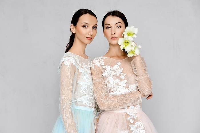 Two beautiful young women in transparent tulle dresses with lace posing in identical manner, Photo by Aleksei Isachenko