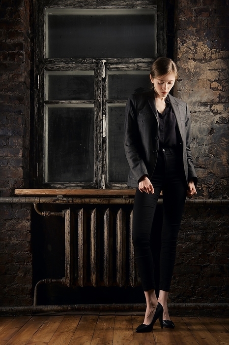 Stylish young woman poising near the window in dark room. Low key full length portrait, Photo by Aleksei Isachenko