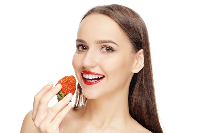 Beautiful happy girl with clean and healthy skin with strawberry near lips. Cosmetology, treatment, beauty and spa, Skin care and aromatherapy, Photo by Aleksei Isachenko