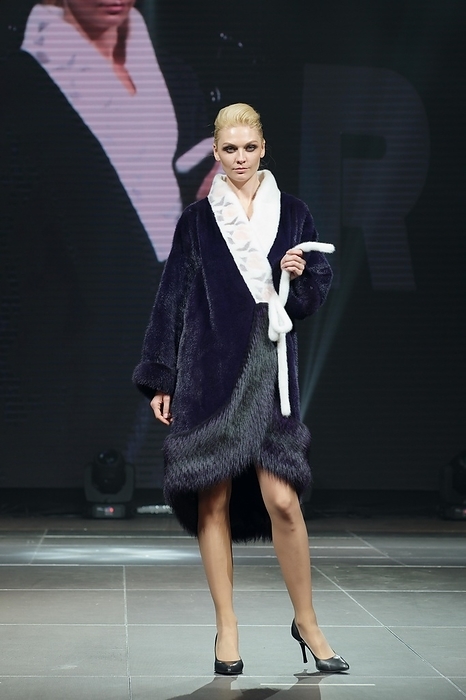 Beautiful fashion model walks on runway in fur coat with online screen on background, Photo by Aleksei Isachenko