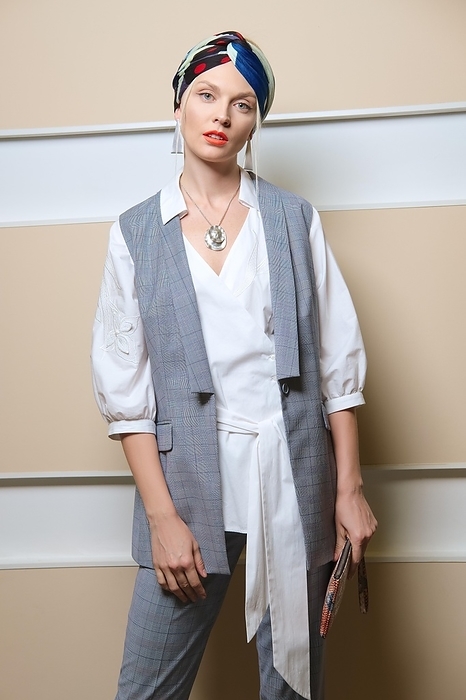 Beautiful fashion model in sleeveless jacket, long asymmetric shirt, pants and turban posing, Photo by Aleksei Isachenko