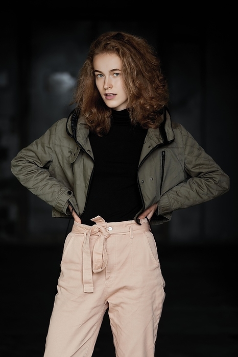 Low key portrait of a student girl in jacket, sweater and trousers, Photo by Aleksei Isachenko