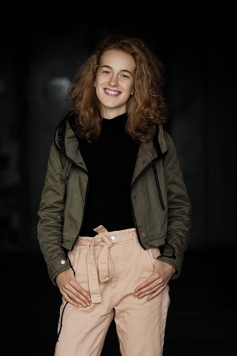 Low key portrait of a student girl in jacket, sweater and trousers, Photo by Aleksei Isachenko