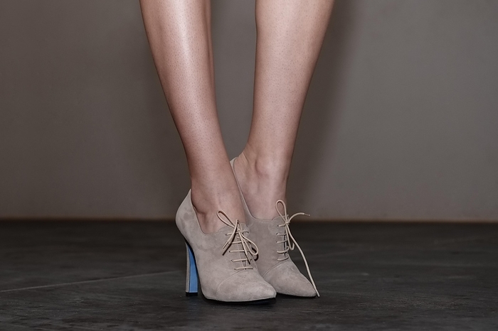 Cropped image of bare female legs in suede boots with shoelaces, Photo by Aleksei Isachenko