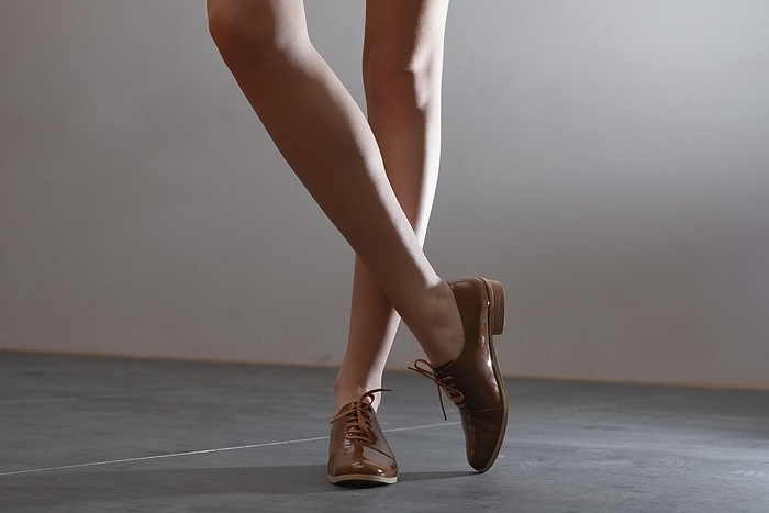 Cropped image of bare female legs in patent leather shoes with shoelaces, Photo by Aleksei Isachenko