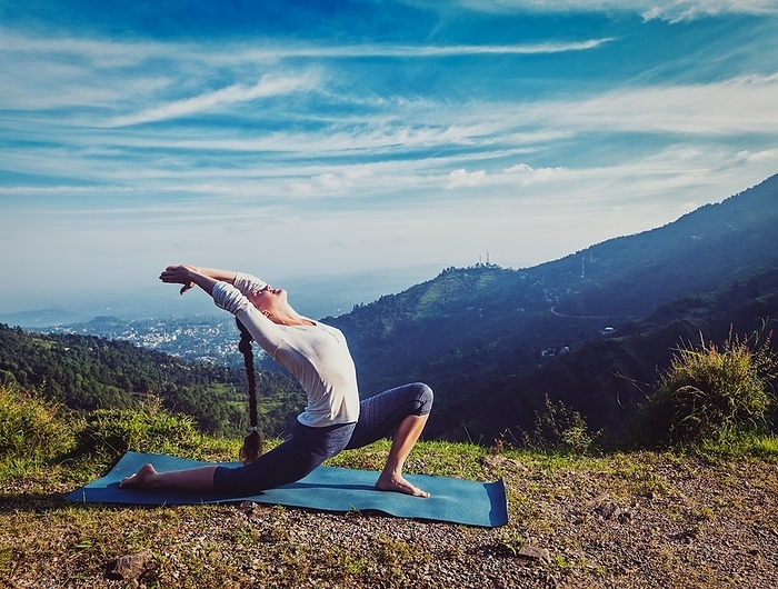 Vintage retro effect hipster style image of sporty fit woman practices yoga Anjaneyasana, low crescent lunge pose outdoors in mountains in morning, Photo by Dmitry Rukhlenko