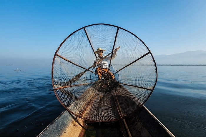 Myanmar travel attraction landmark, Traditional Burmese fisherman with fishing net at Inle lake in Myanmar famous for their distinctive one legged rowing style, view from boat, Photo by Dmitry Rukhlenko
