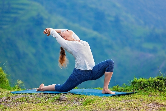 Yoga outdoors, sporty fit woman practices Hatha yoga asana Anjaneyasana, low crescent lunge pose posture outdoors in Himalayas mountains, Photo by Dmitry Rukhlenko