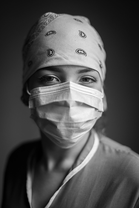 Interior intimate portrait of latina female health worker wearing a face mask and a nurse cap during Covid-19 pandemic, Photo by Nano Calvo / VWPics