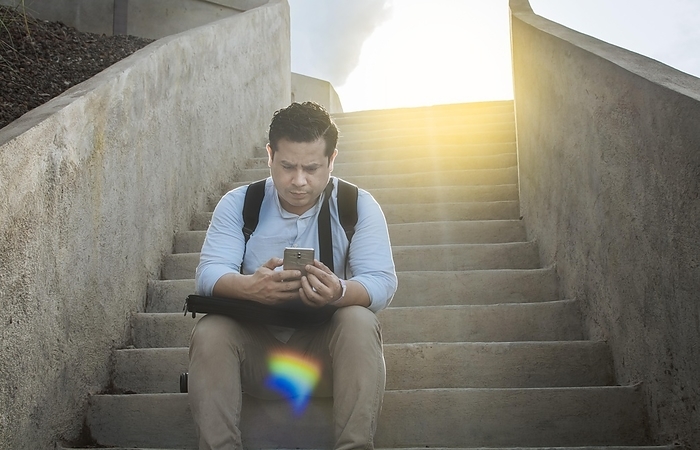 Handsome man sitting on stairs using smart phone, Front view of guy sitting on stairs using his cell phone outdoors, Close up of young man sitting on stairs using mobile phone outdoors, Photo by Isai Hernandez