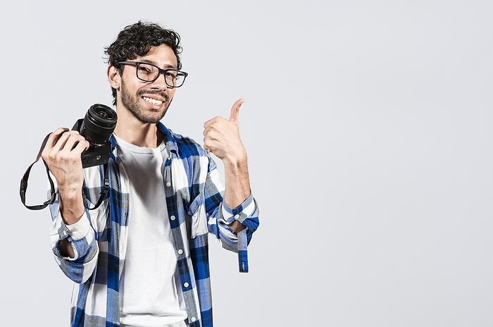 Smiling male photographer showing a camera and giving thumb up. Young man holding a camera and giving the thumb up, Smiling guy photographer showing a camera with thumb ok, Photo by Isai Hernandez