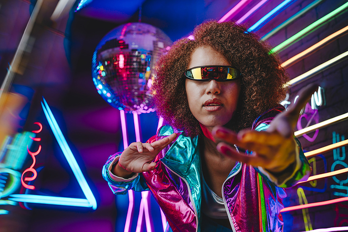 Woman wearing VR glasses gesturing in front of neon light