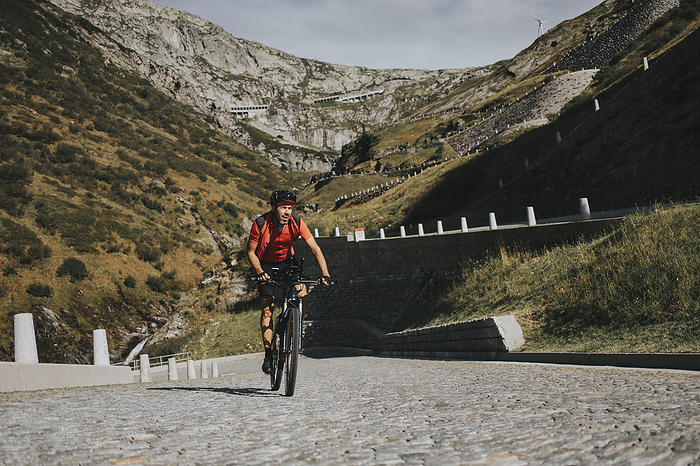 Man cycling through Gotthard Pass on sunny day