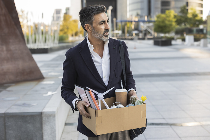 Fired businessman holding office supplies in box