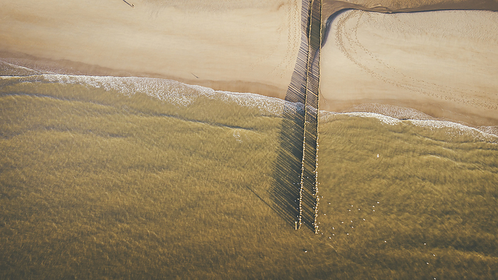 Drone view of wooden posts over sea at beach
